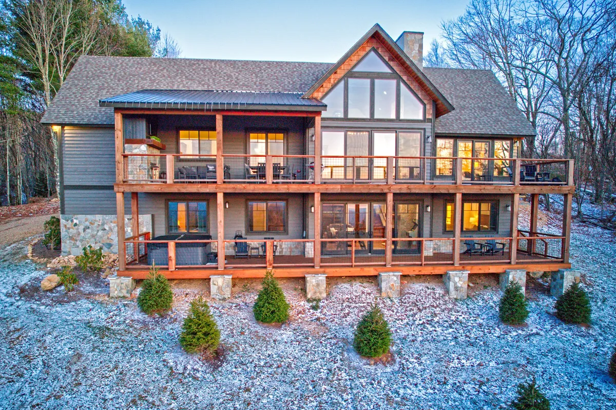 A spacious wooden balcony with large windows overlooks lush greenery, providing an ideal setting for family barbecues, gatherings, or quiet morning coffee. The integration of indoor and outdoor elements invites guests to flow between activity and leisure.
