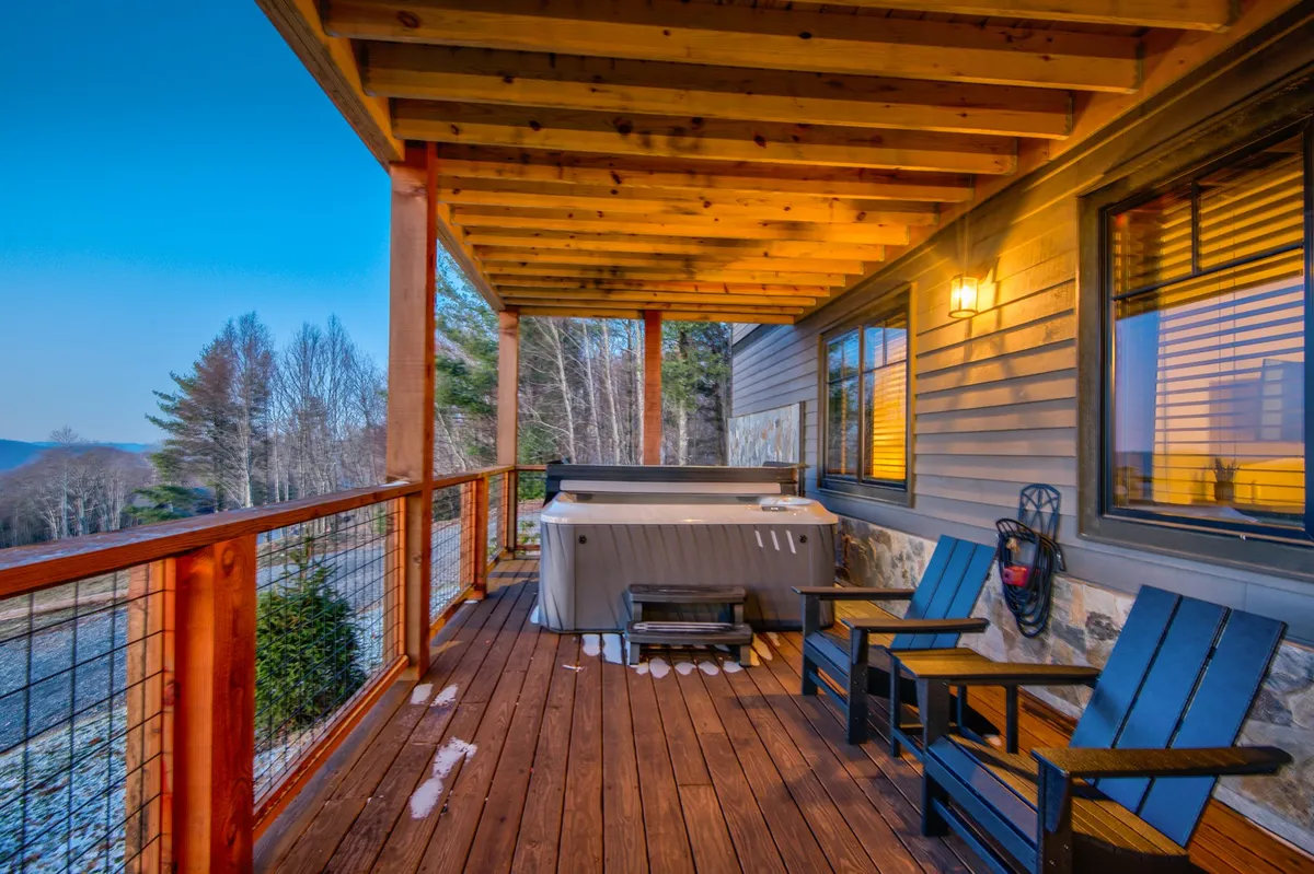 An outdoor hot tub set on a wooden deck overlooking a beautiful mountain view. The scene is tranquil and inviting, ideal for a soothing soak while enjoying sunset views or stargazing in the crisp air.